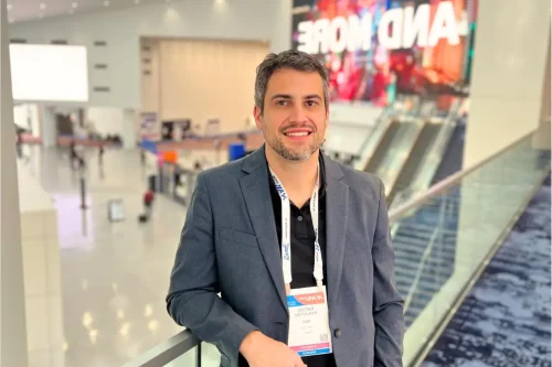 Foto de Rafael Parlatore durante um evento. Ele veste terno, sorri para a foto e tem um crach&aacute; do evento no pesco&ccedil;o.